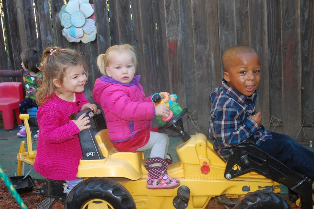 Three children on yellow ride-on toys