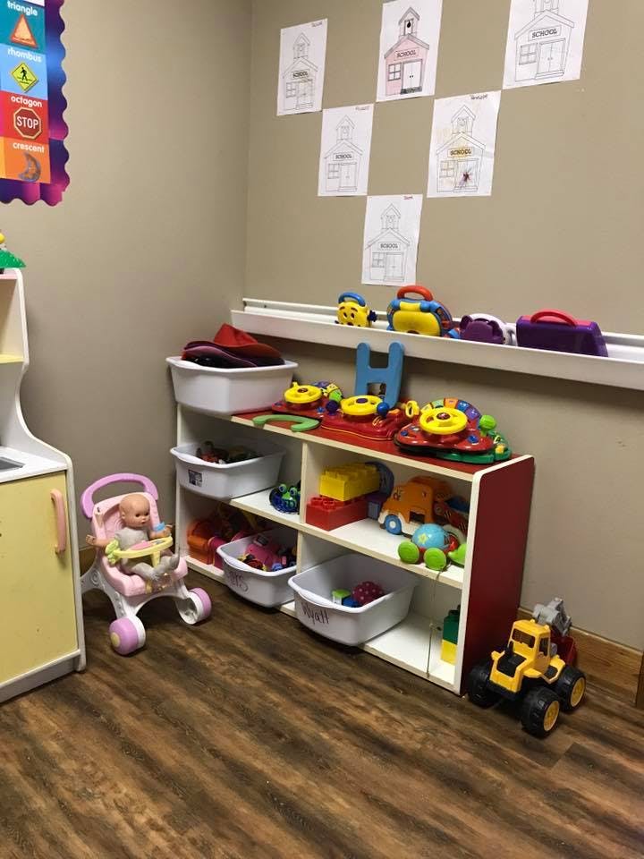 Playroom with shelves of toys, a doll in a stroller, and drawings on the wall