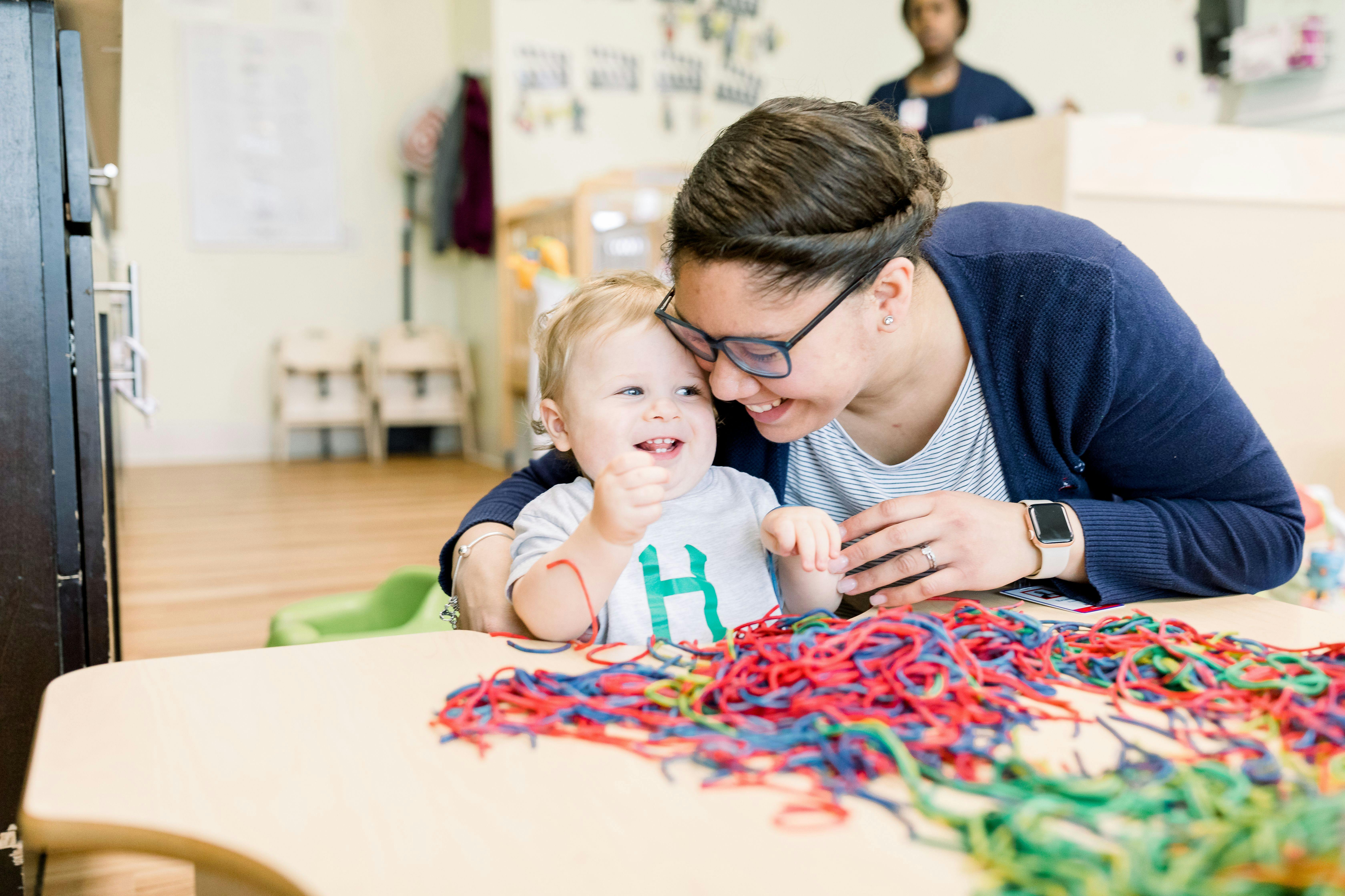 Adult and child playing with colorful strings at a table