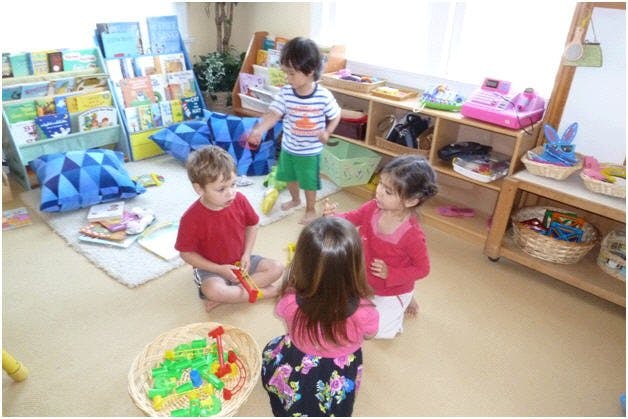 Four children playing with toys in a classroom