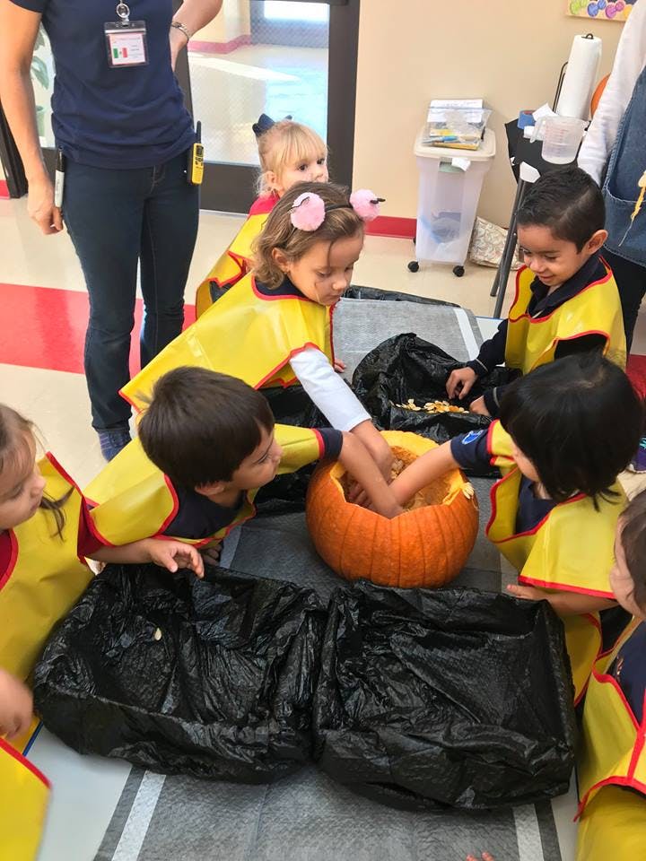 Children carving a pumpkin in a classroom