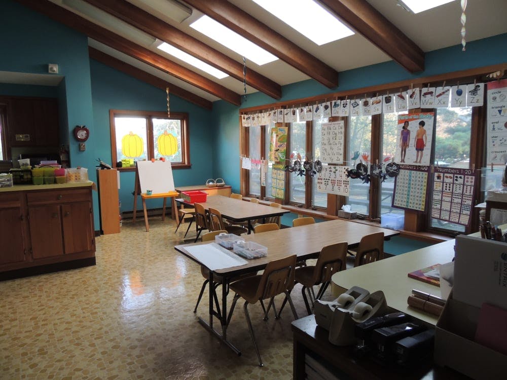Classroom with tables, chairs, and windows decorated with papers