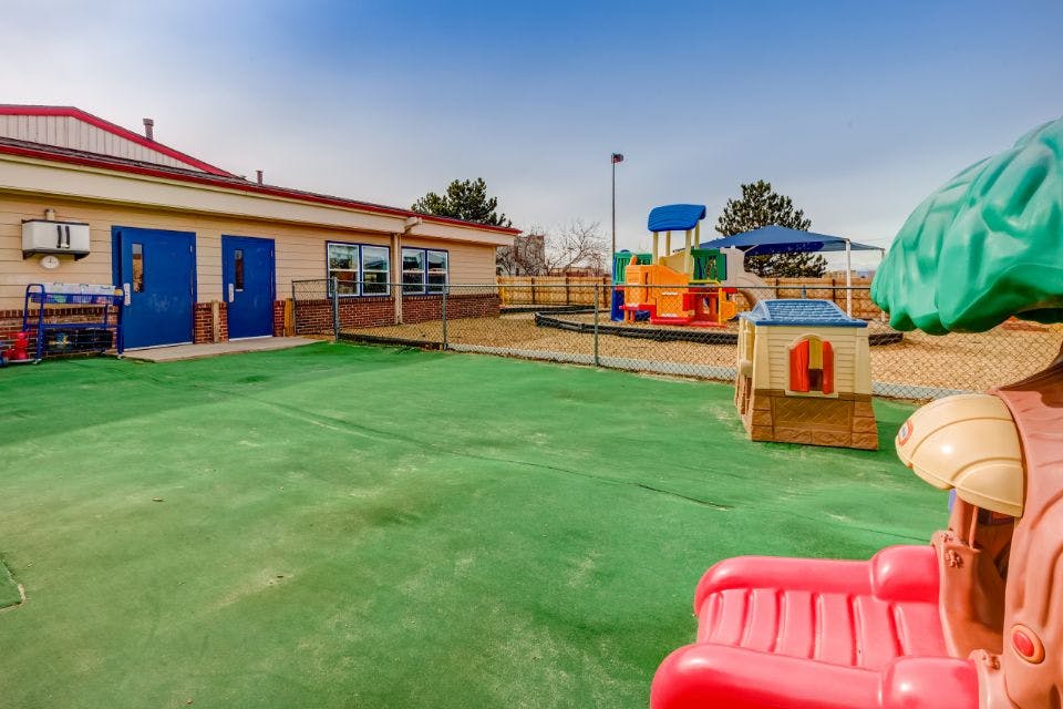 Outdoor playground with green turf, building, and play structures