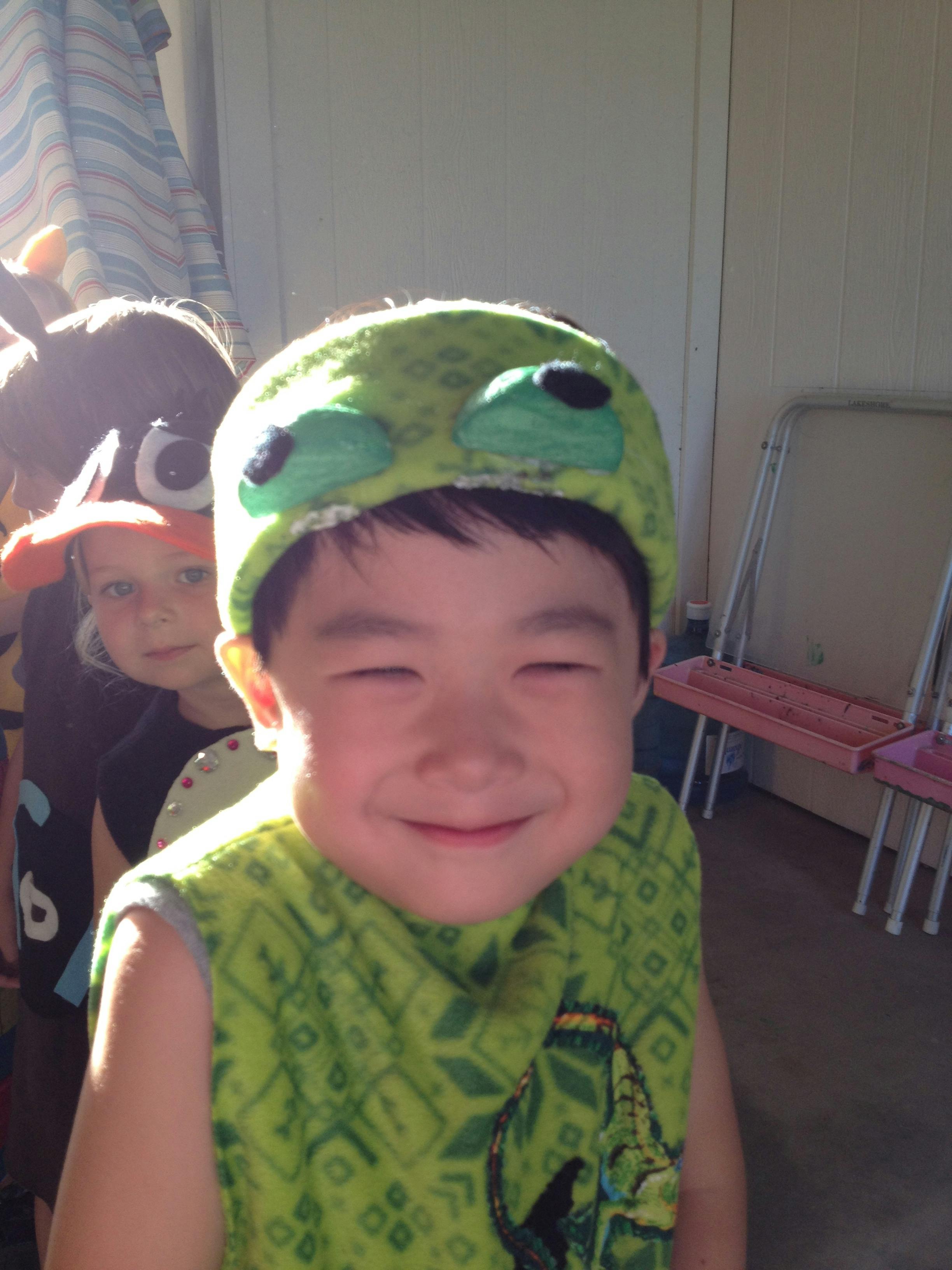 Child in a green hat with eyes, smiling