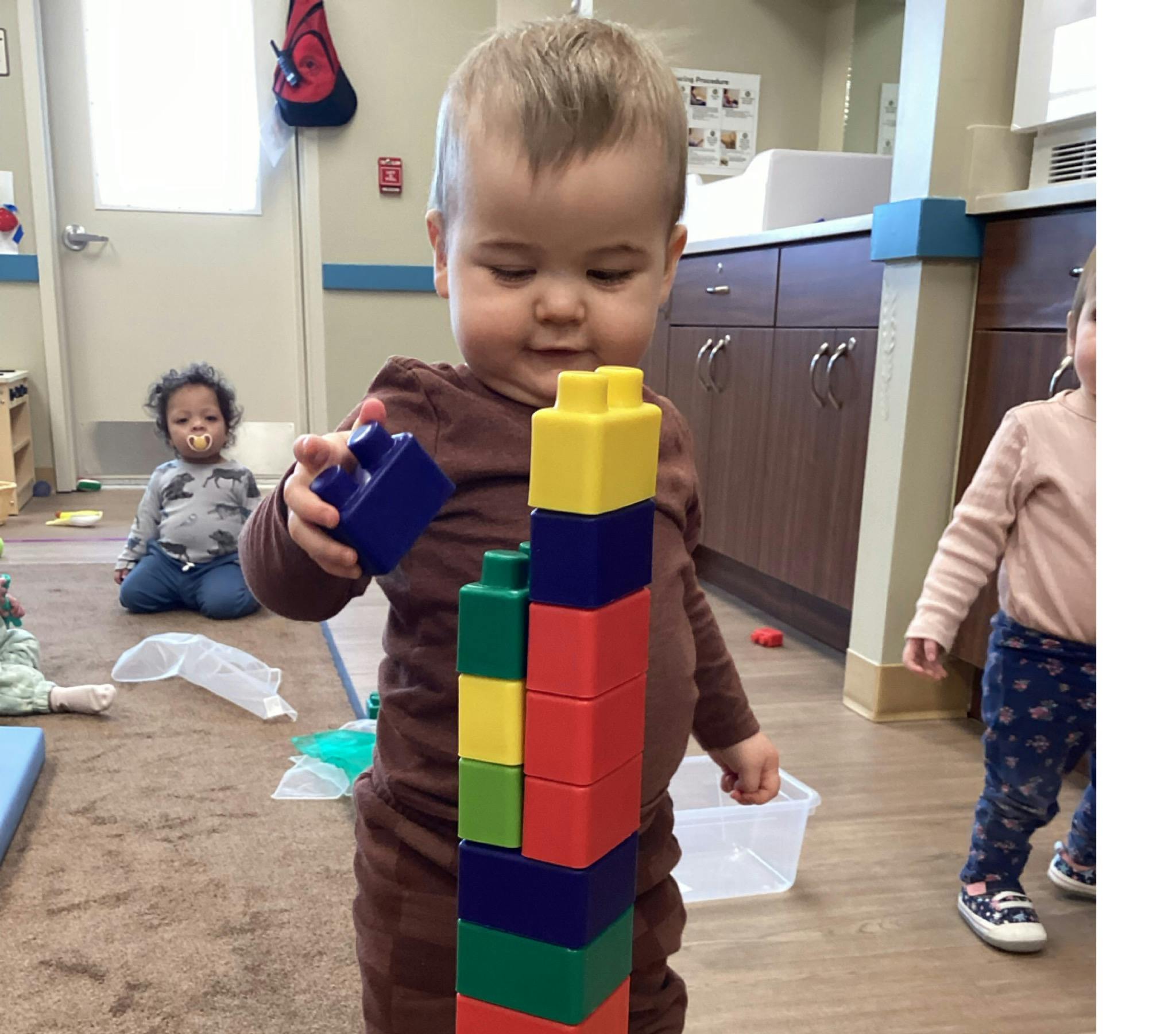 Child building a tall block tower in a classroom
