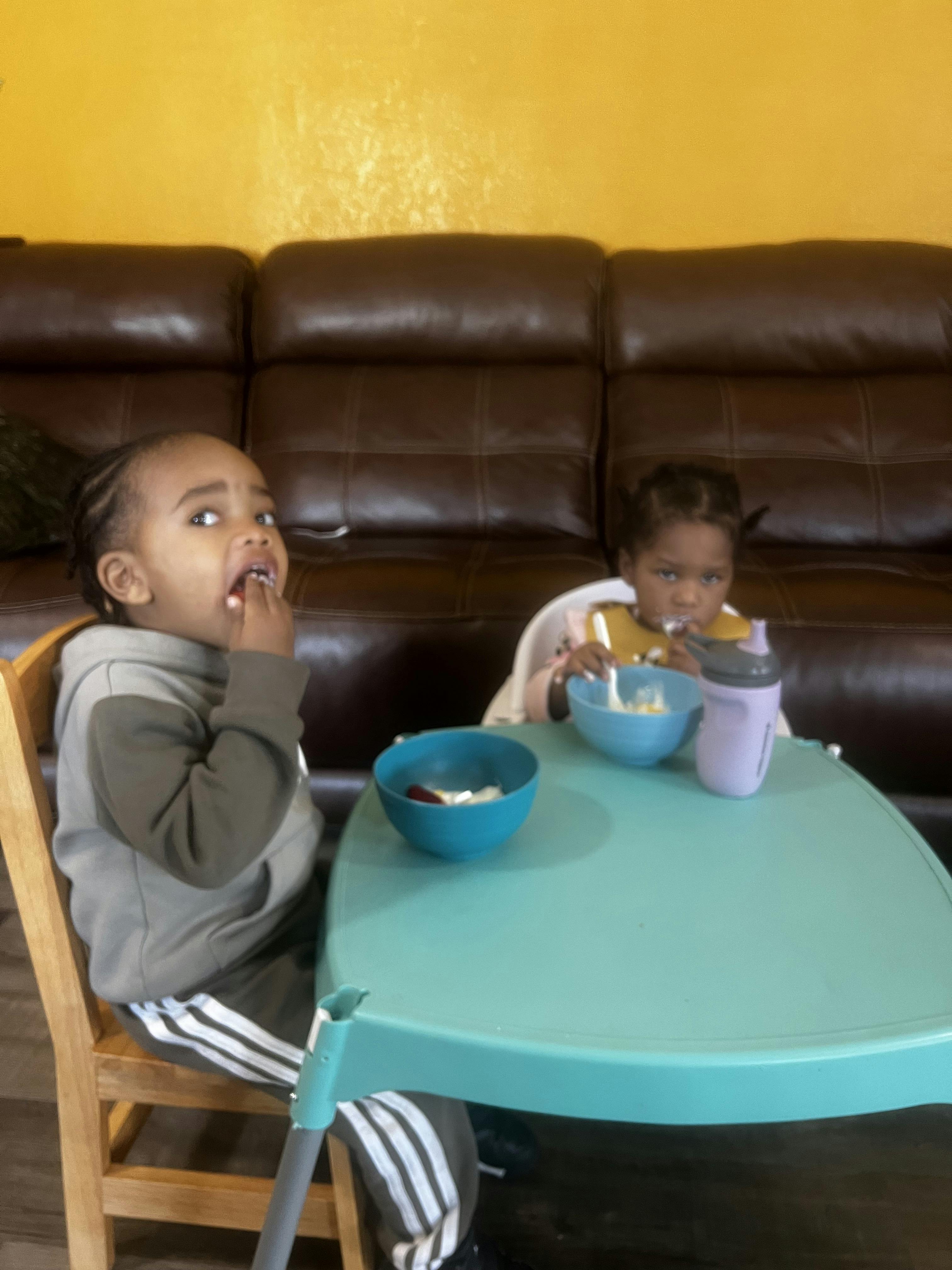 Two children sitting at a table with bowls of food