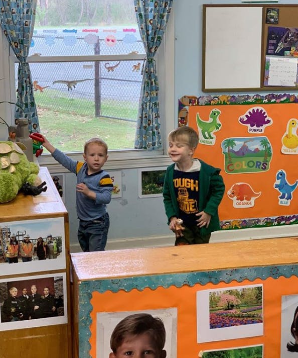 Two children in a classroom, one holding a toy