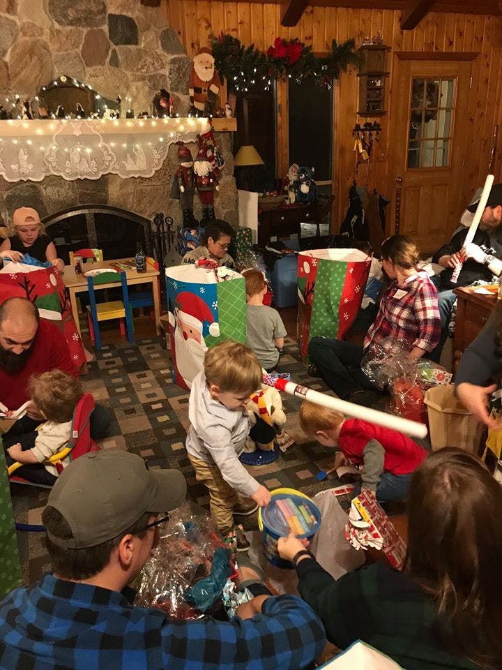 People and children opening gifts in a room decorated for Christmas