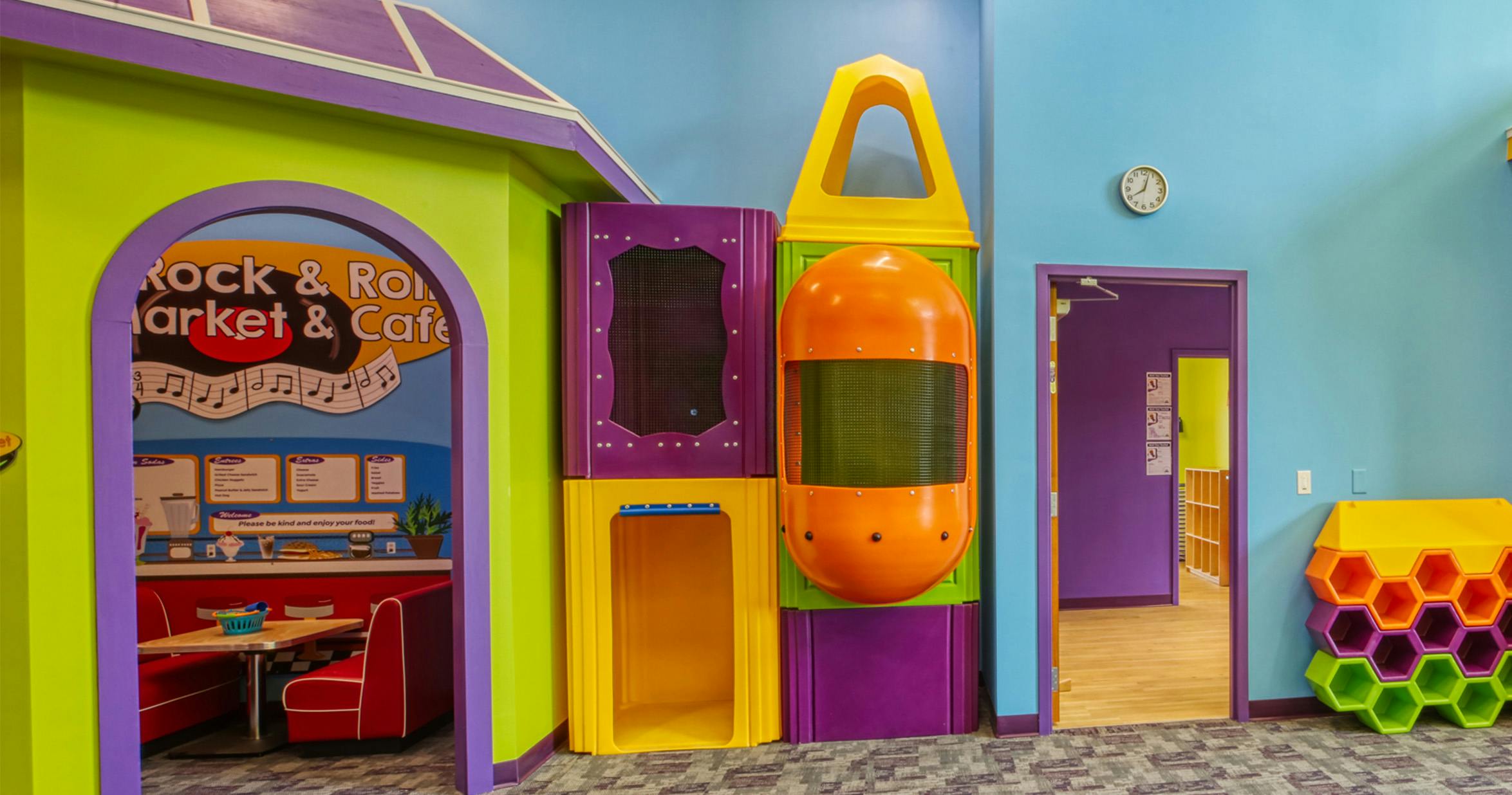 Colorful indoor play structure with a cafe area on the left