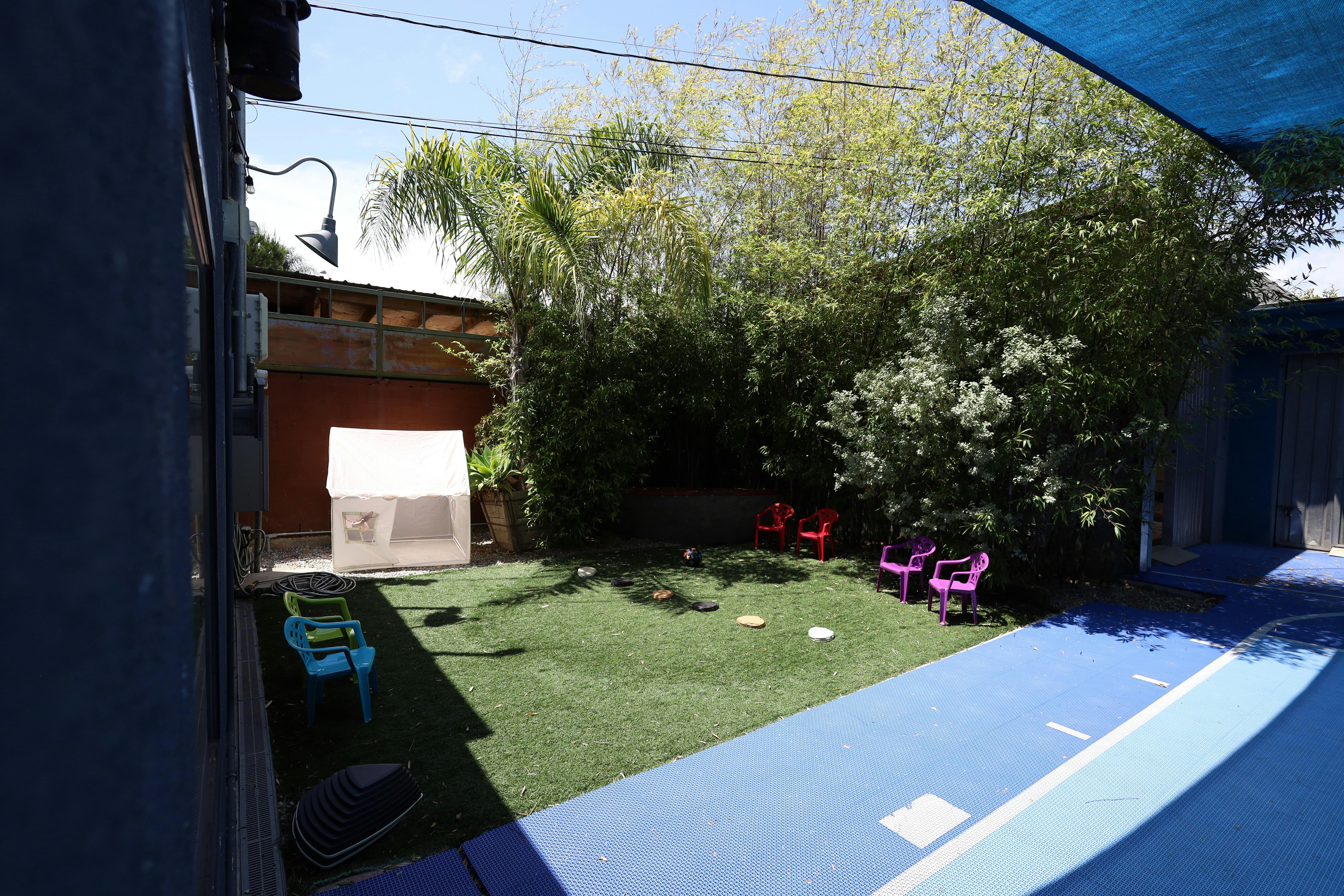 Small backyard area with artificial turf, play tent, and child-sized chairs