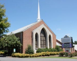 Brick church with a tall white steeple and arched windows