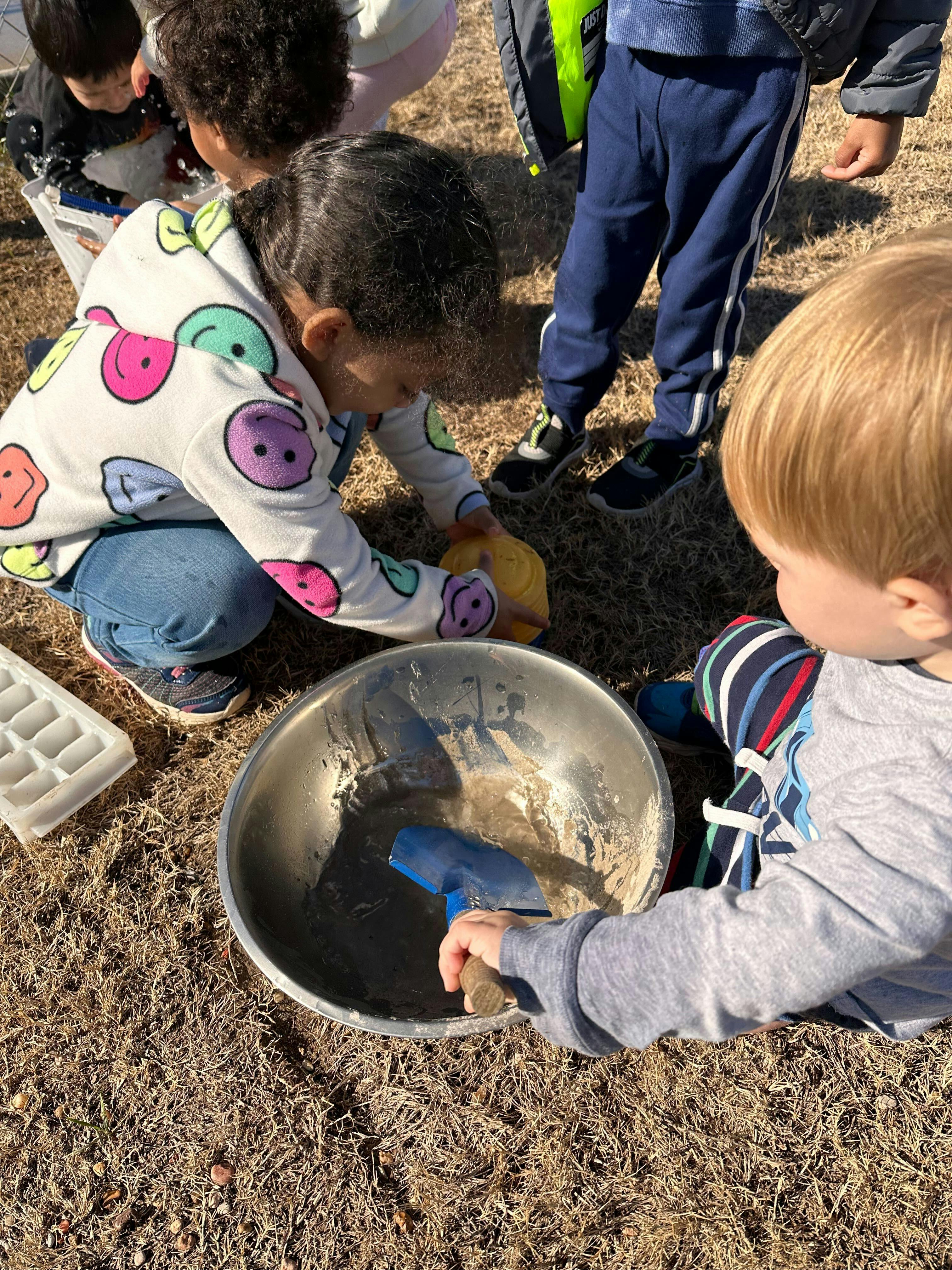 Child playing with dirt in a bowl with a trowel
