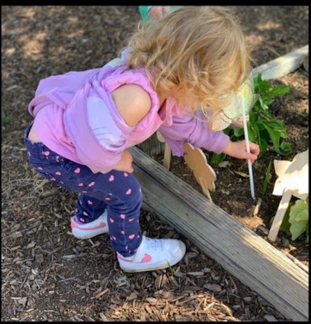 Child bending down and painting a plant