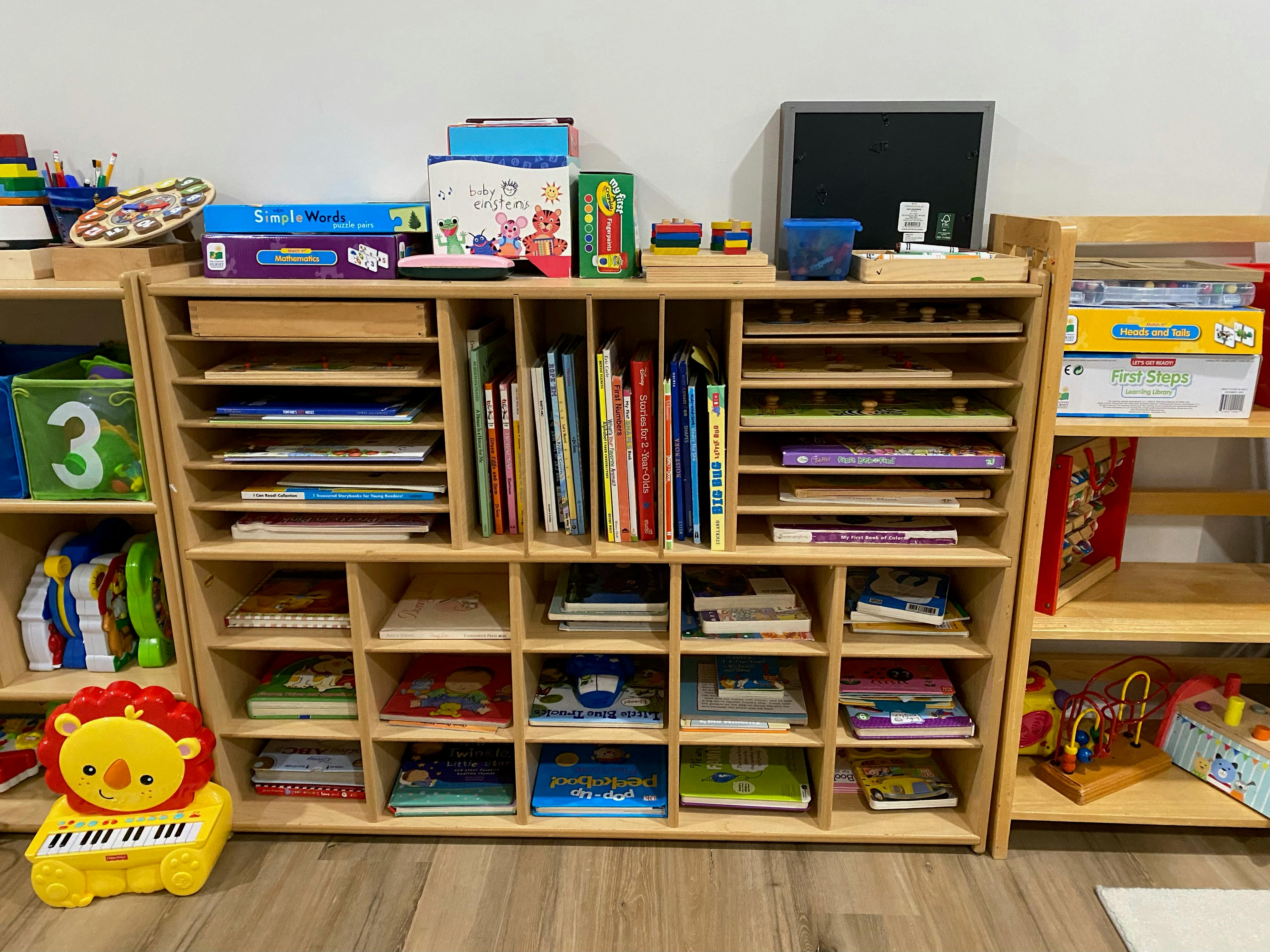 Wooden shelves filled with books, puzzles, and learning materials in a classroom