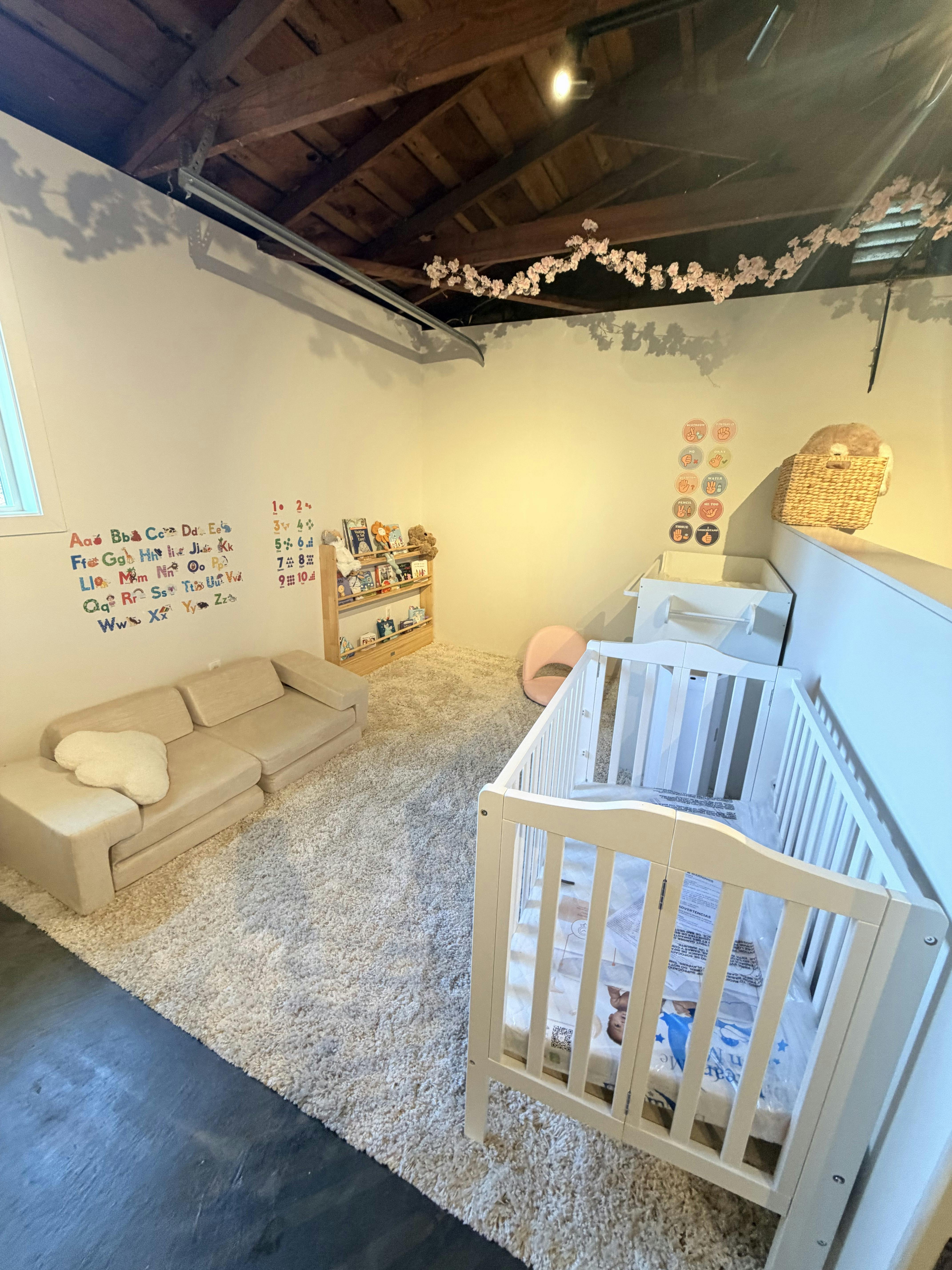 A furnished nursery with a crib, small sofa, and bookshelf