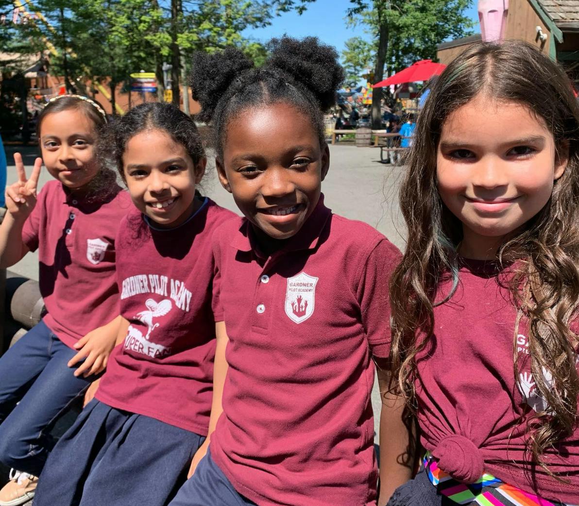 Four children in matching shirts smiling at the camera