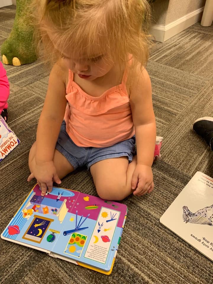 Child sitting on floor looking at an open book