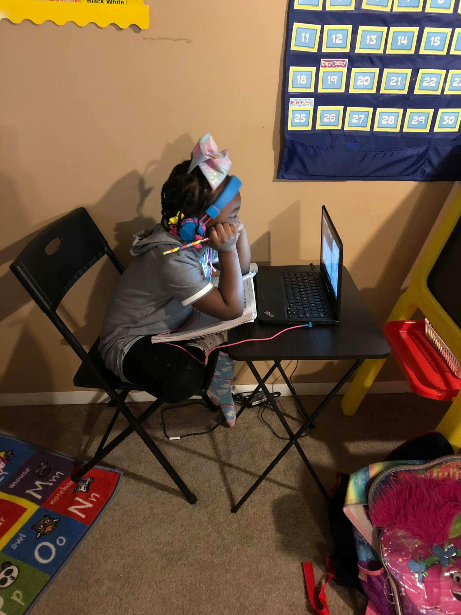 Child wearing headphones and looking at a laptop
