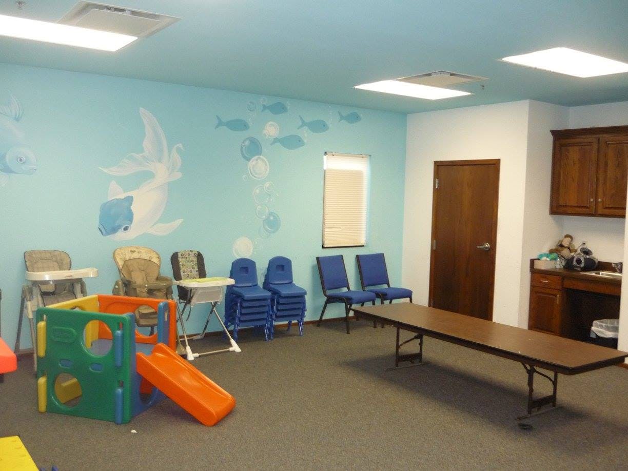 Indoor play area with a slide, chairs, and a long table