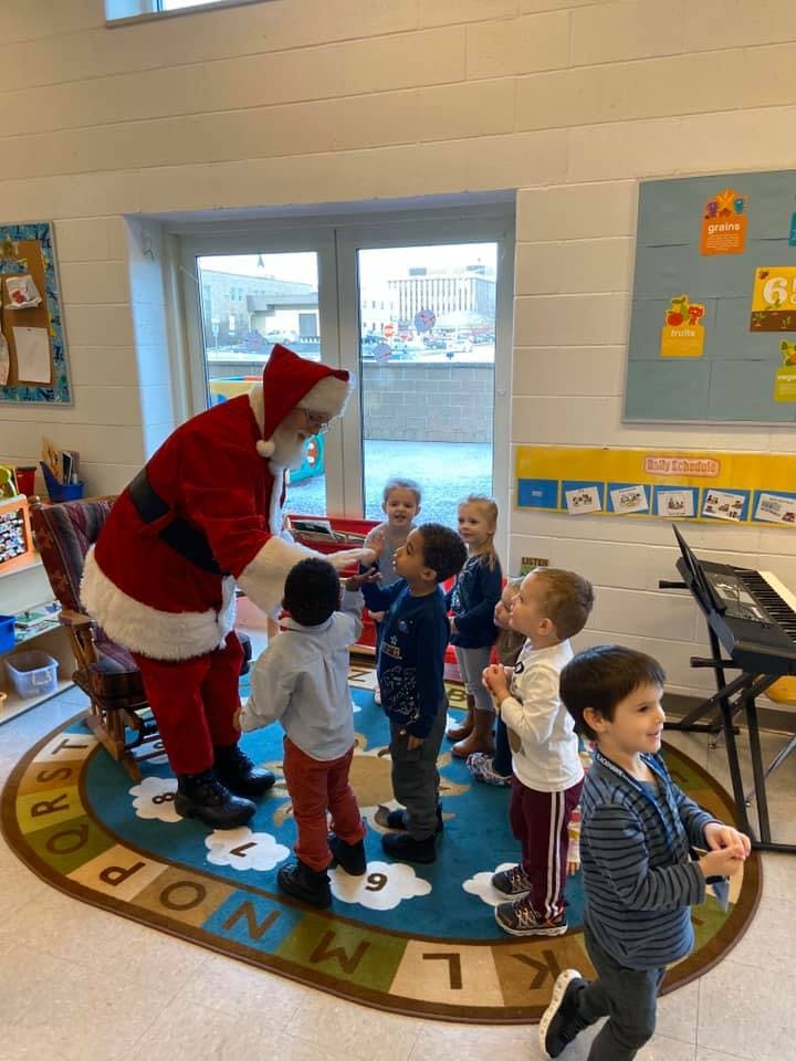 Person dressed as Santa Claus interacting with children in a classroom