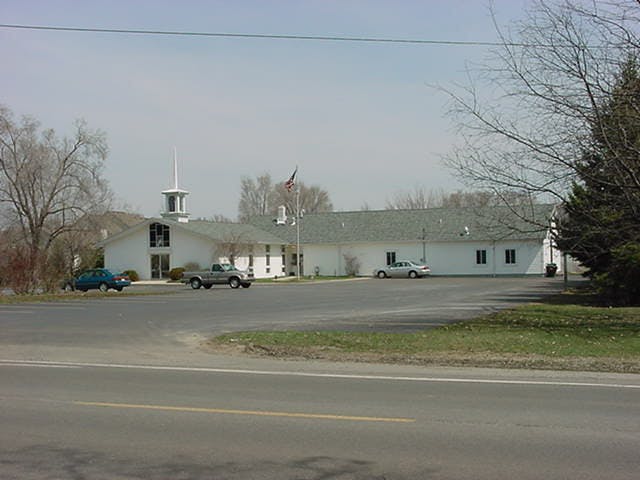 White building with a steeple and a parking lot