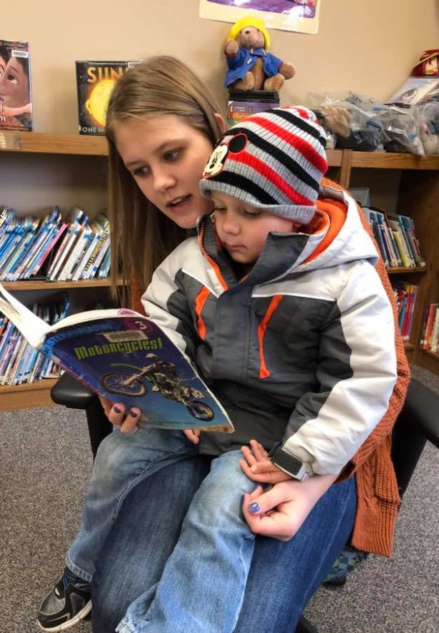 Person reading a book to a child sitting on their lap
