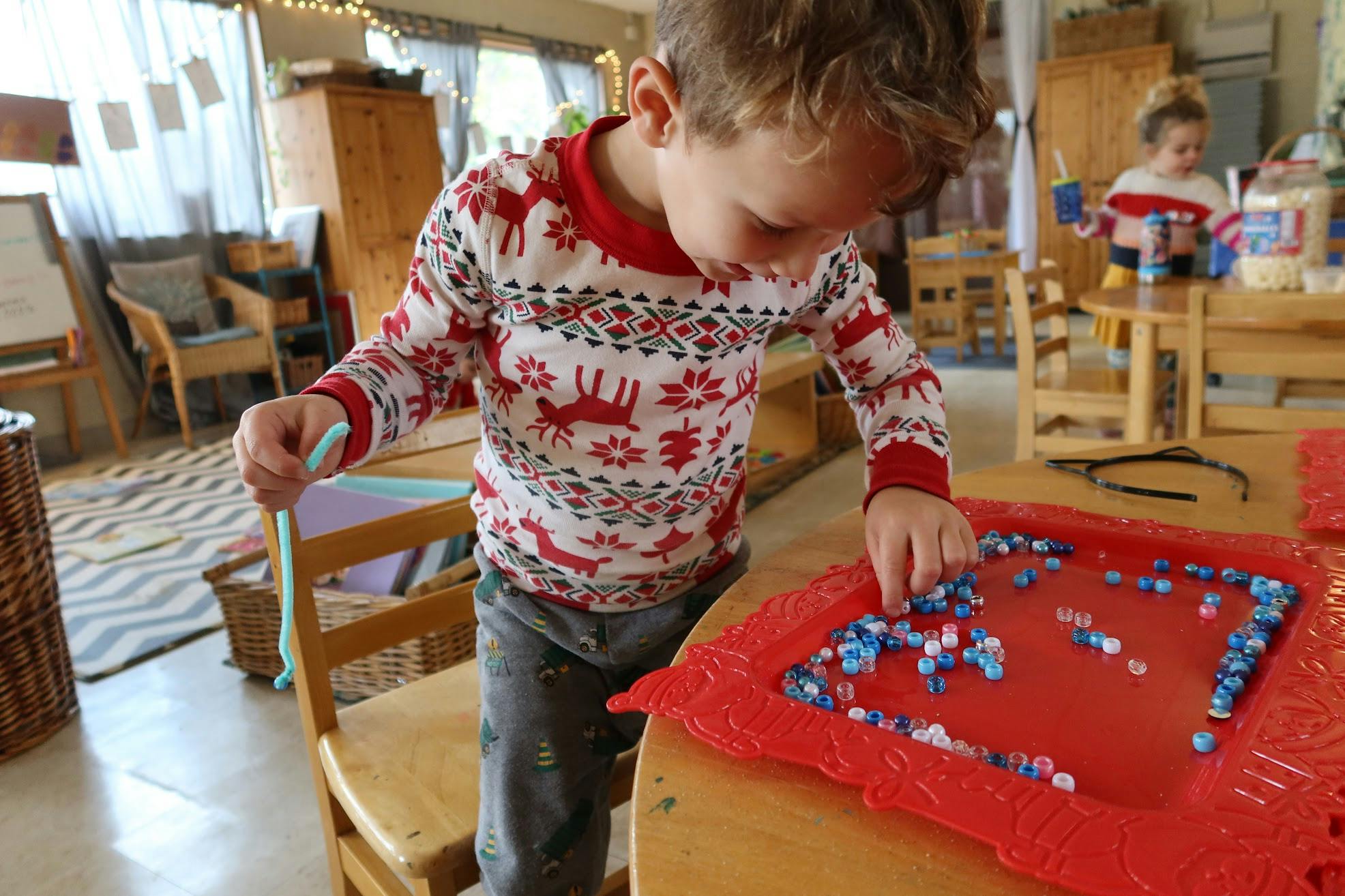 Child playing with beads on a red tray