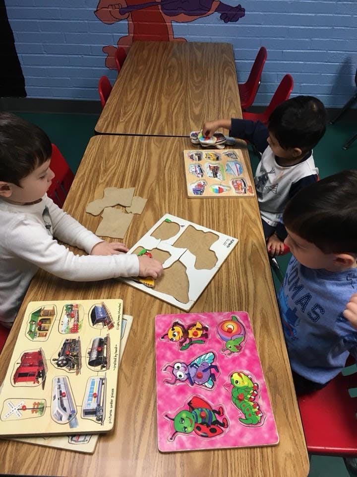 Three children playing with puzzles at a table