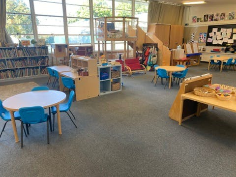 Classroom with small tables and chairs, bookshelves, and play structures