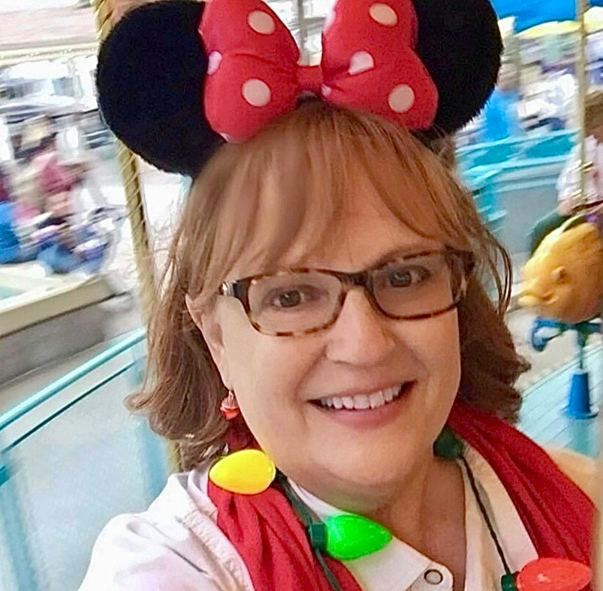 Person with Minnie Mouse ears and a string of Christmas lights around their neck
