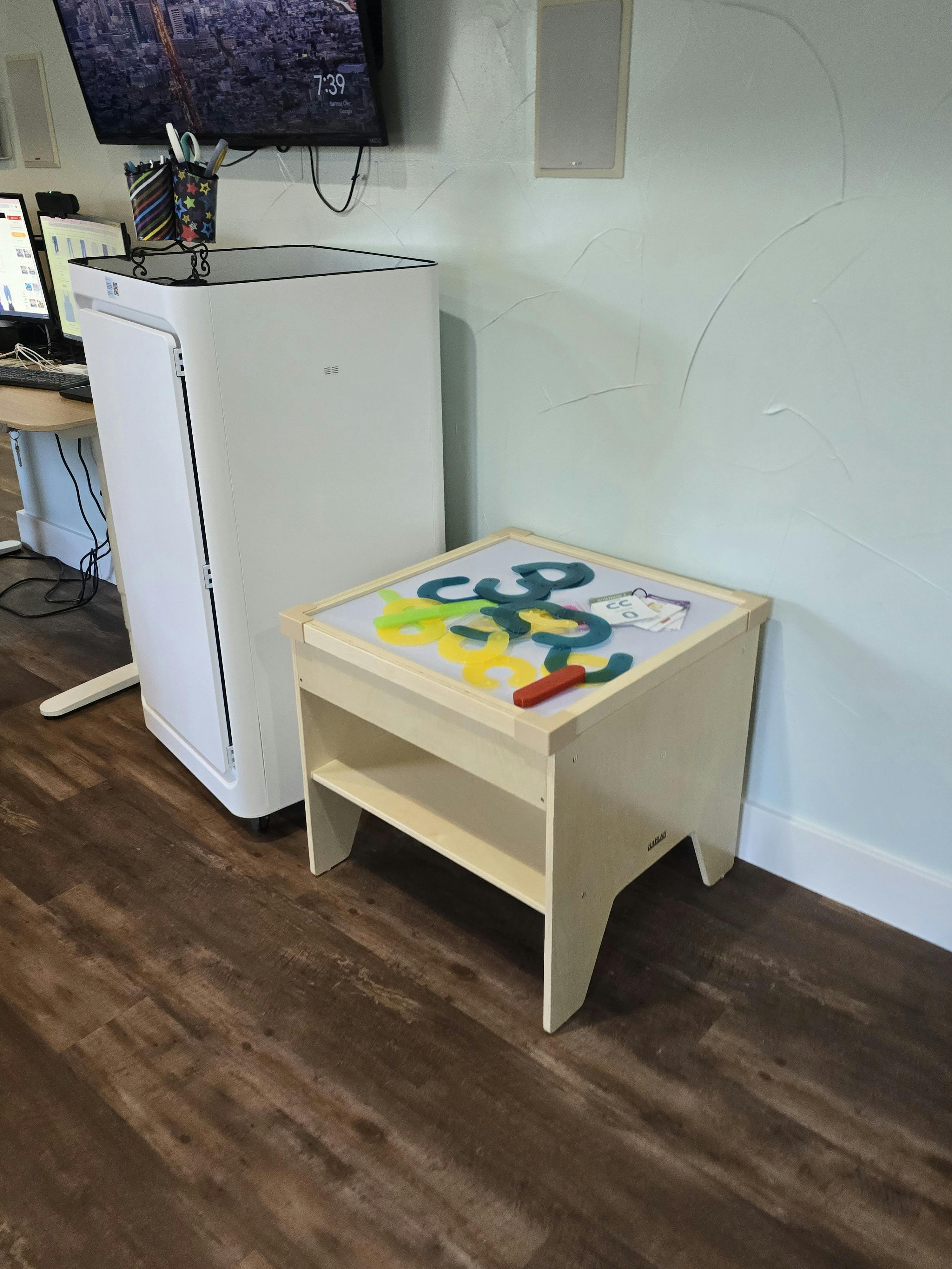 Air purifier next to a child's activity table with colorful shapes