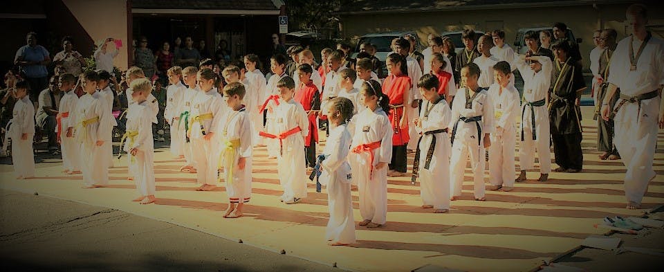 Group of children and adults in martial arts uniforms standing in uniform