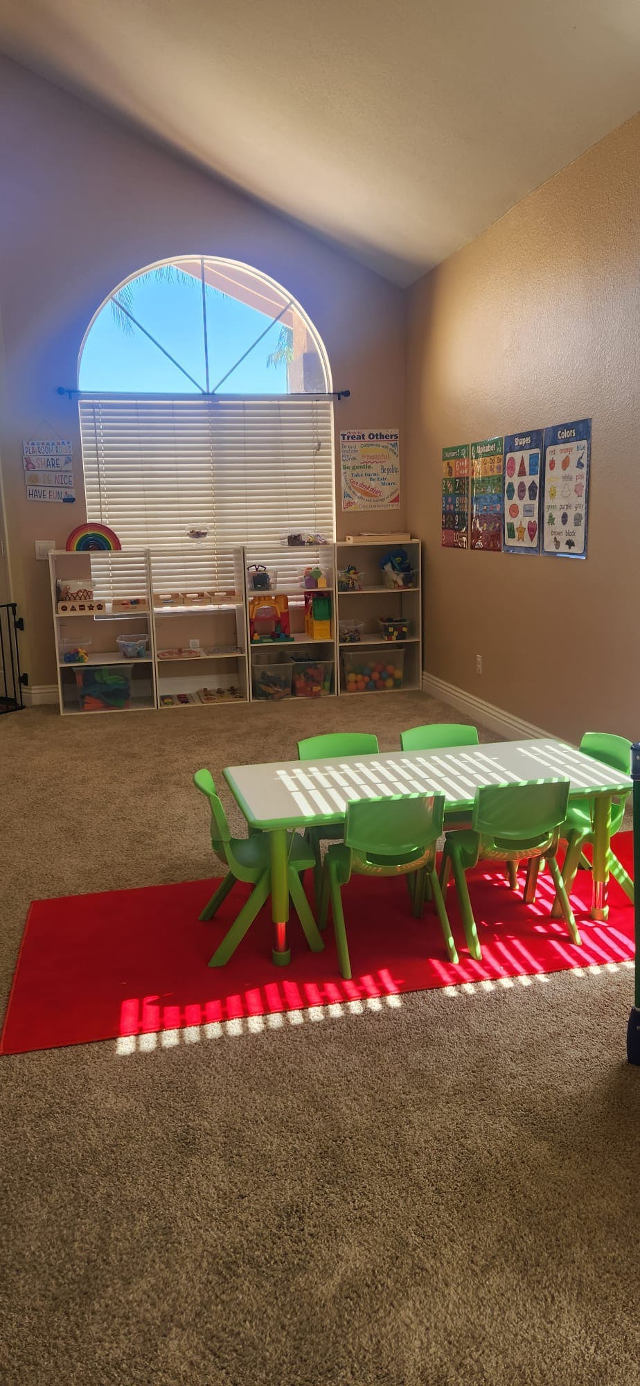 Classroom with a table and chairs, shelves with toys, and posters on the wall