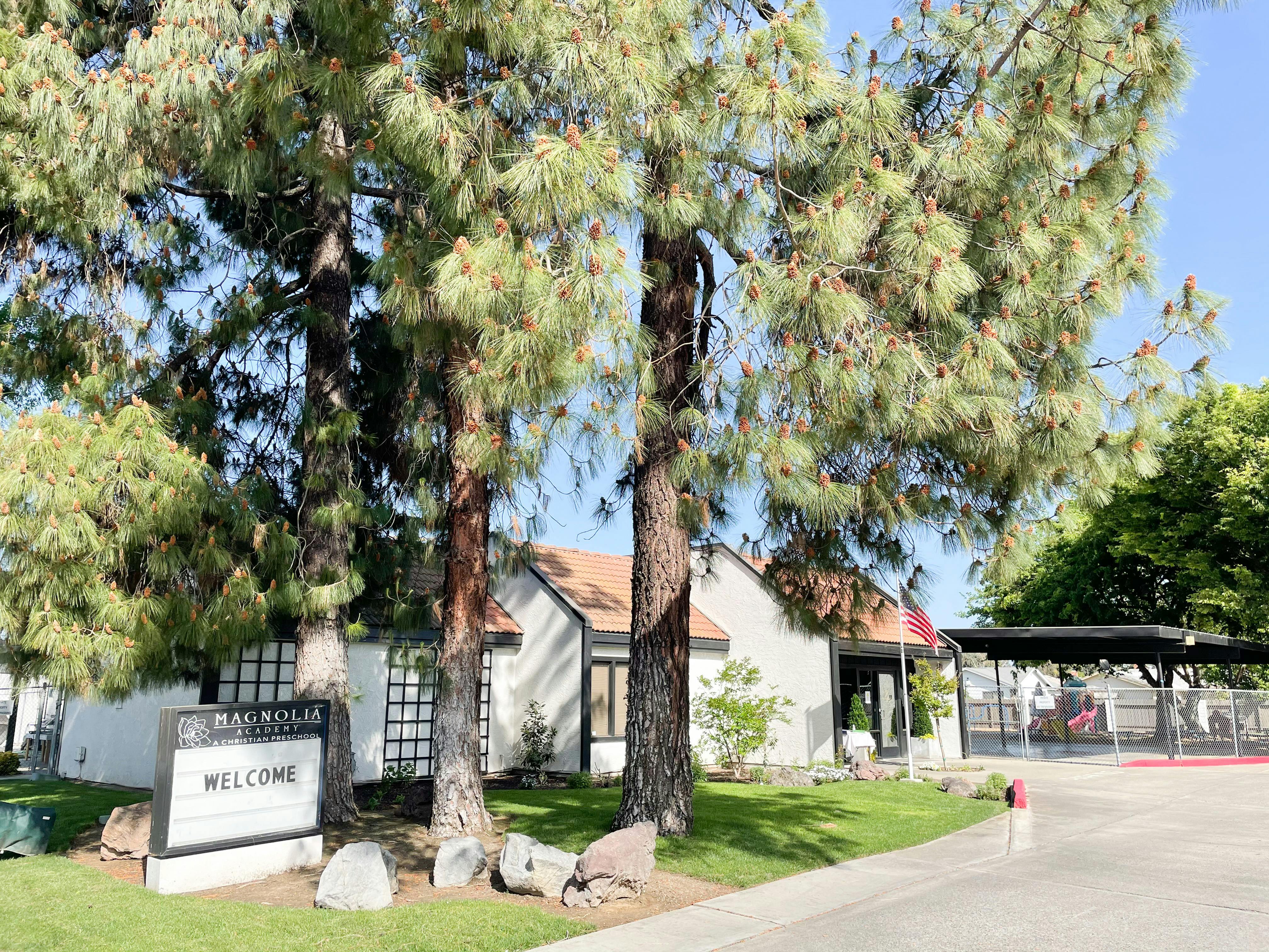 Building with a welcome sign and tall trees in front