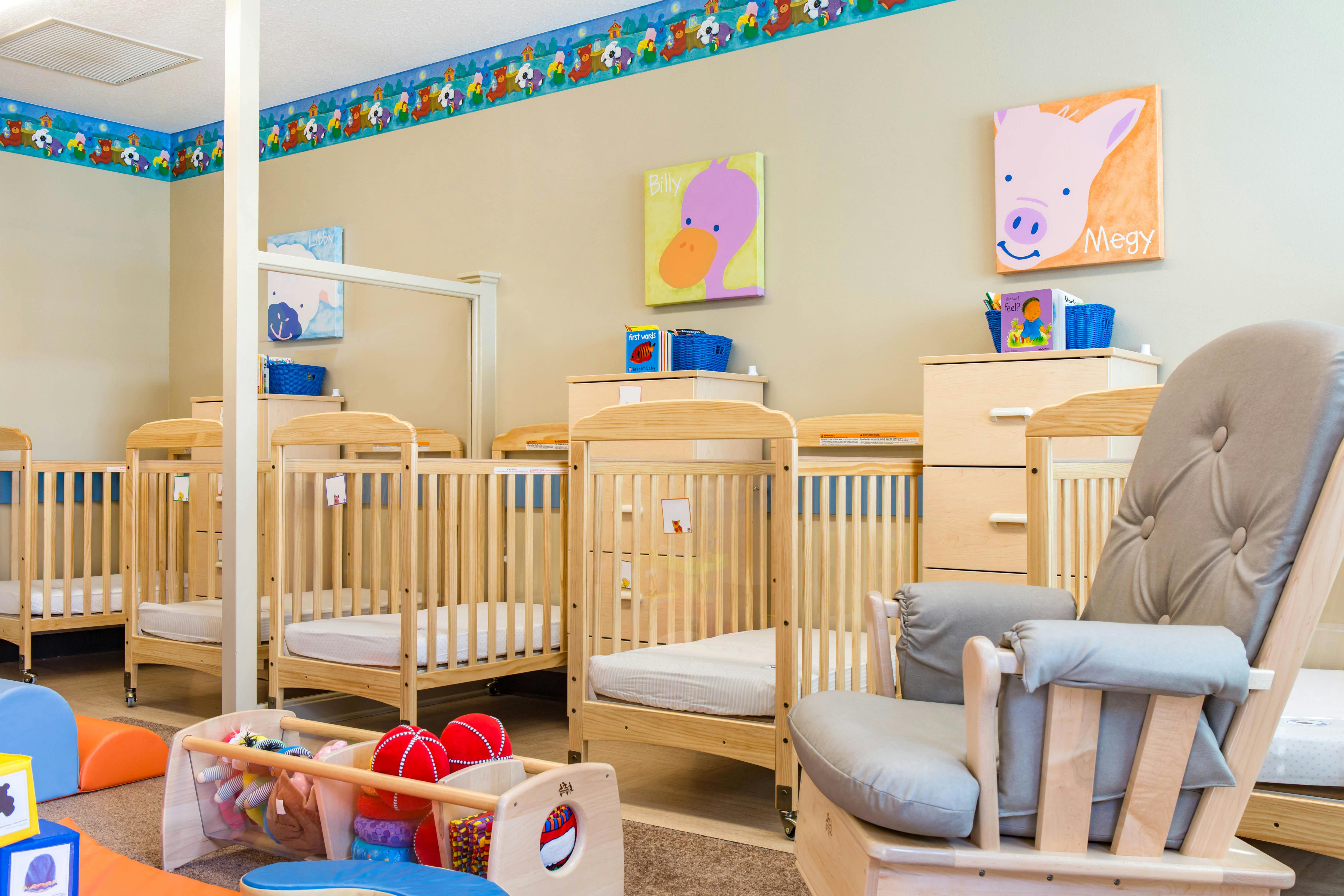 cribs in a daycare or nursery room with colorful wall decorations