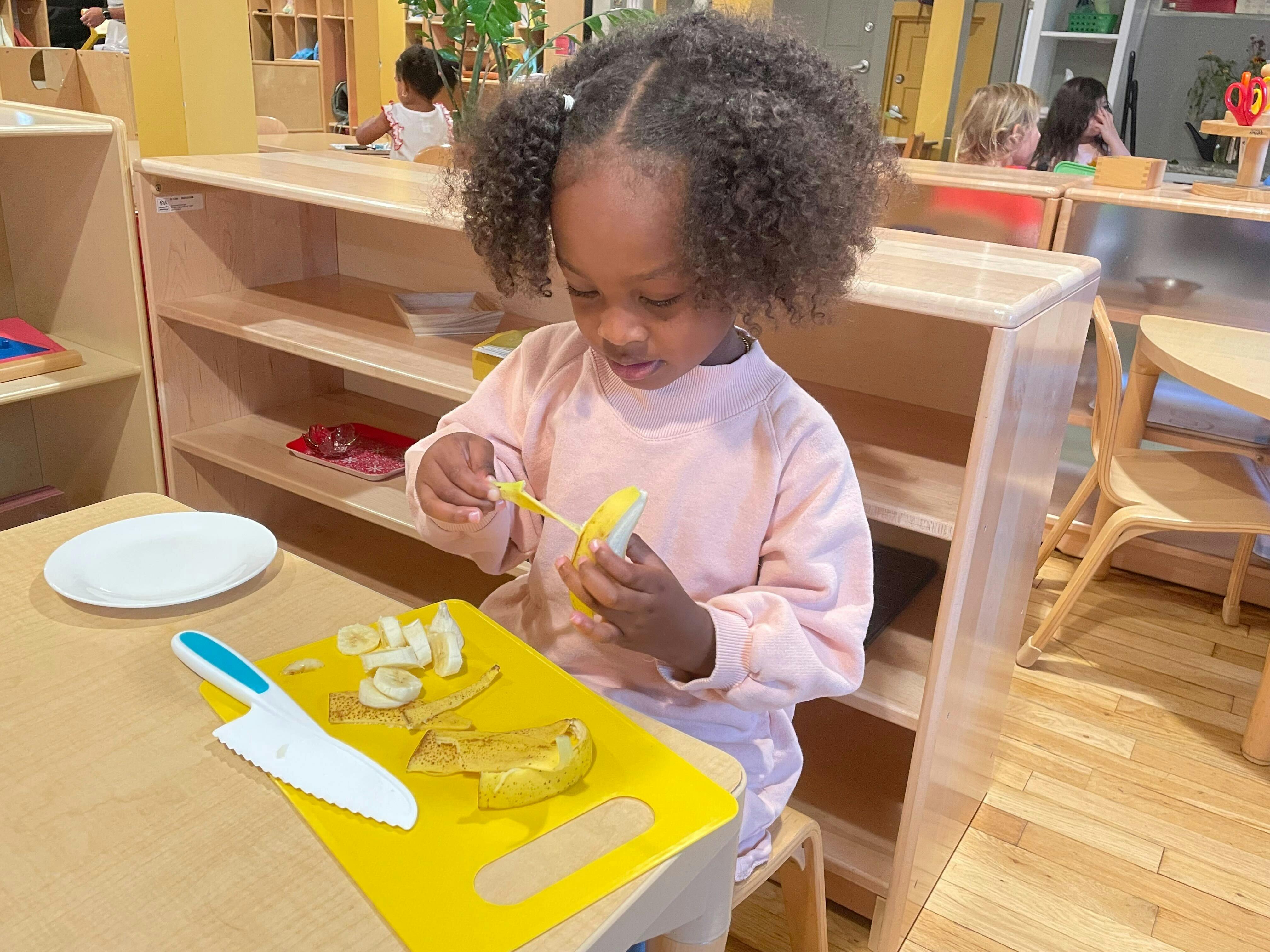 Child peeling a banana in a classroom