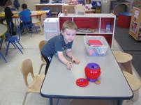 Child playing with a toy on a table in a classroom