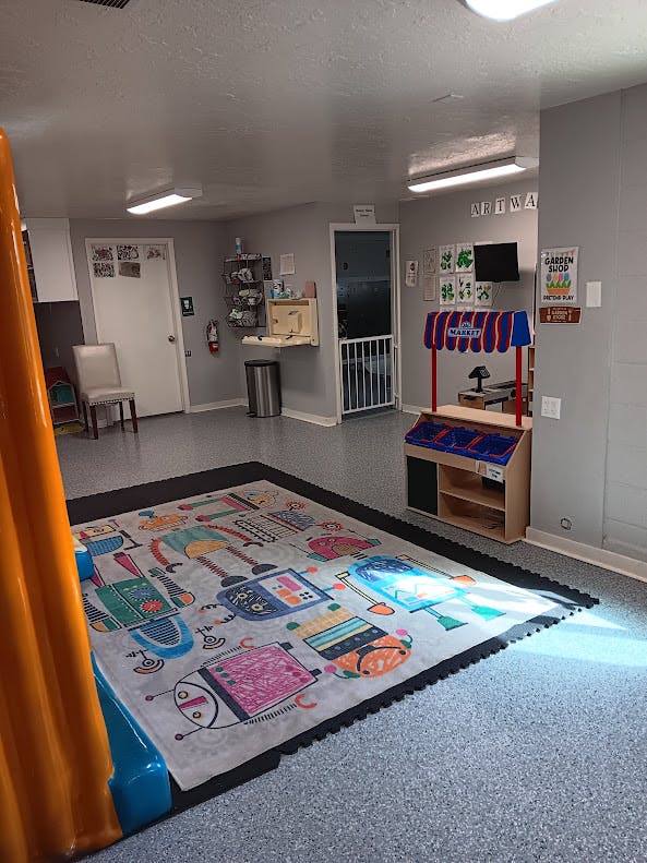 Playroom with a robot-themed rug, a play market stand, and a changing station