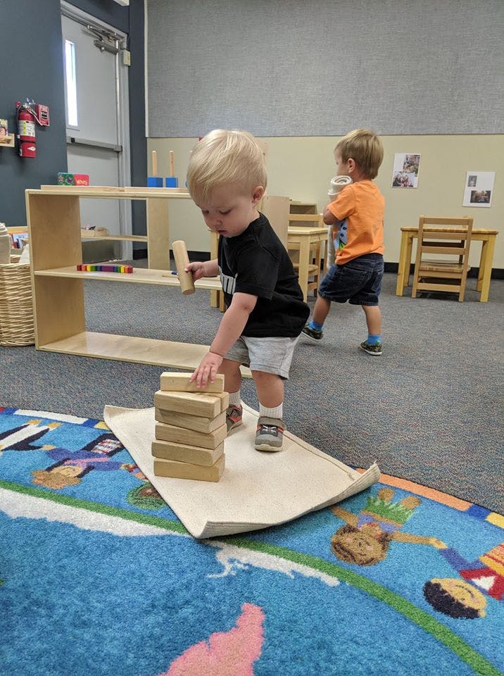 Child stacking wooden blocks in a classroom