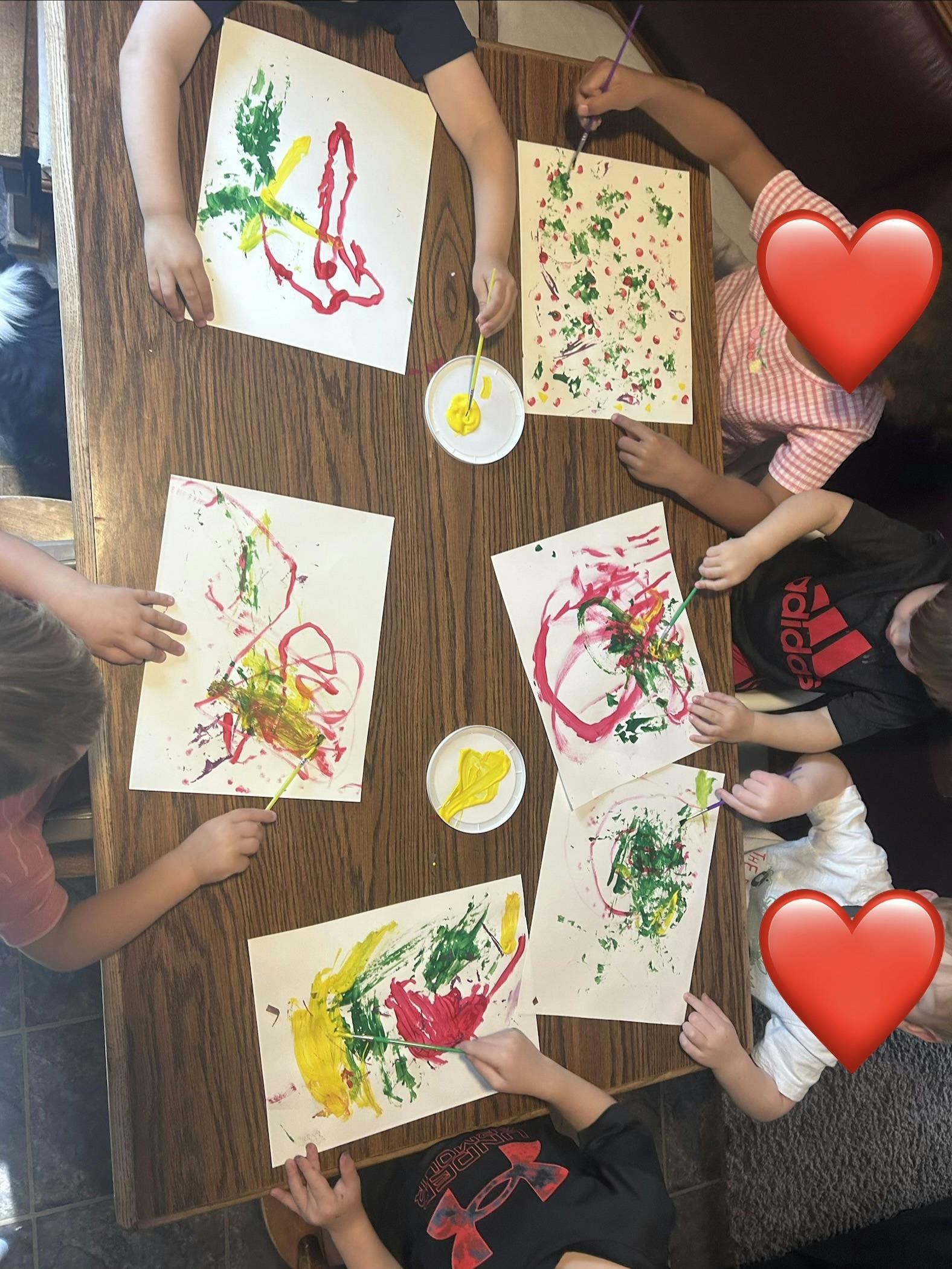 Group of children painting with brushes on paper at a table