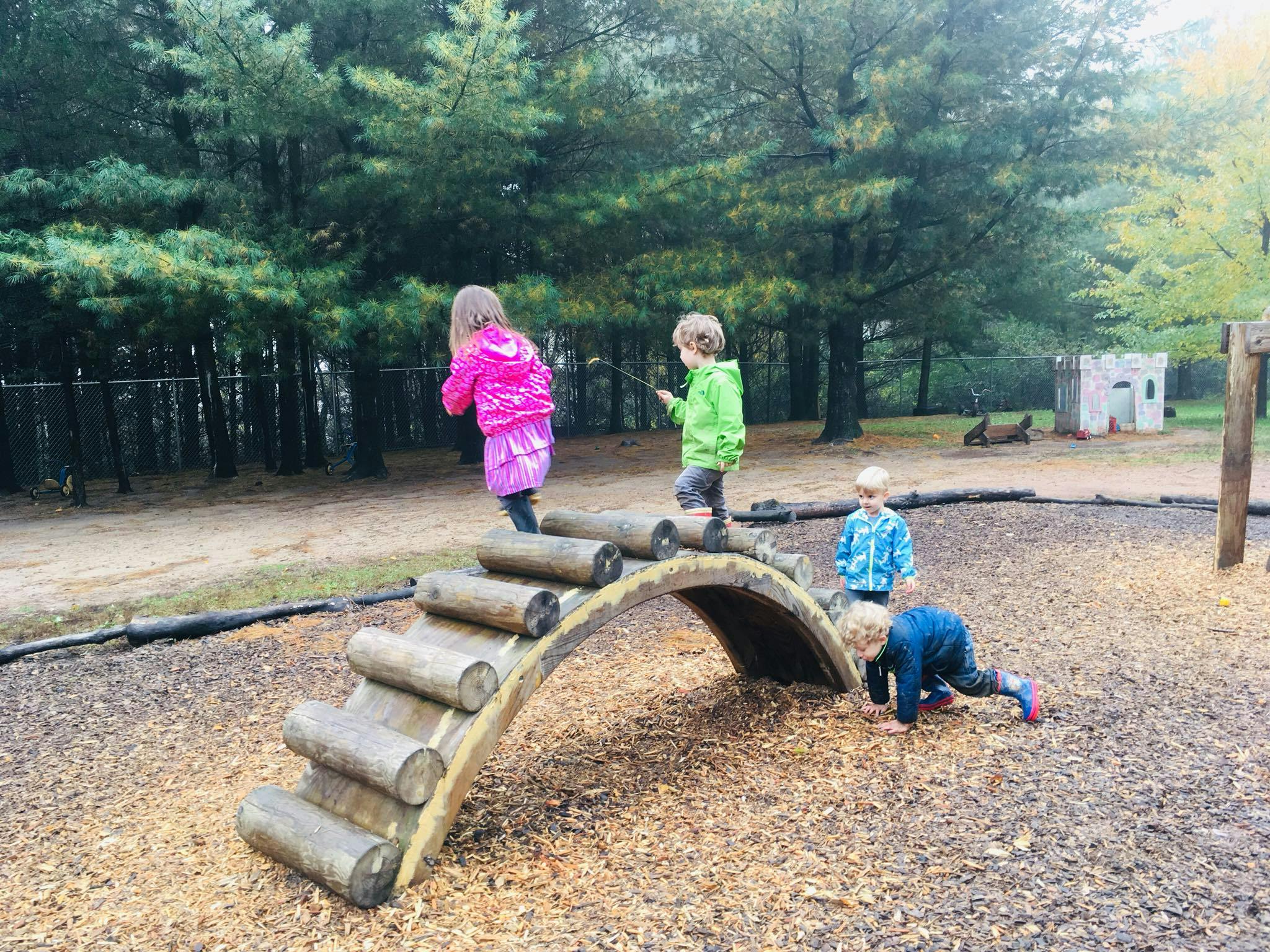 Children playing on a wooden climbing structure in a playground