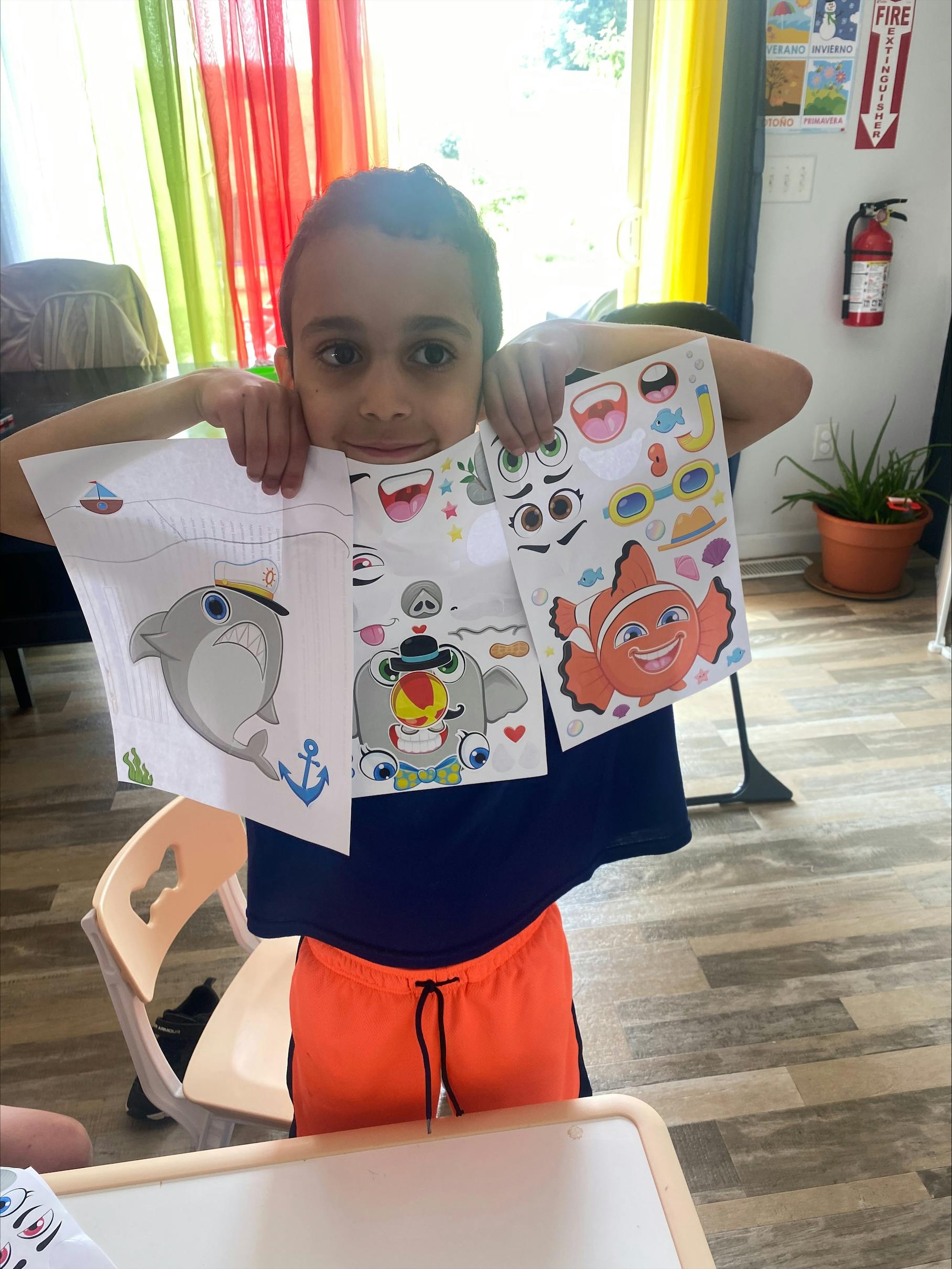Child holding up three sheets of paper with cartoon sea creatures