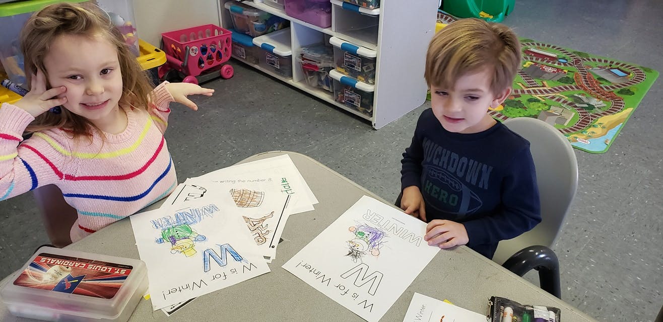 Two children drawing at a table