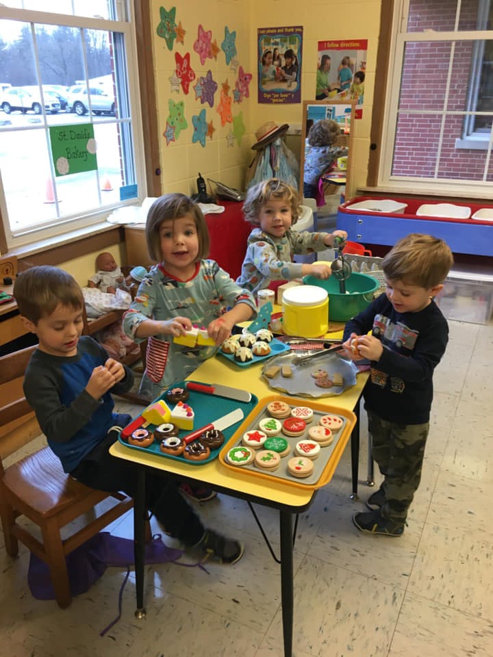 Four children decorating cookies at a table