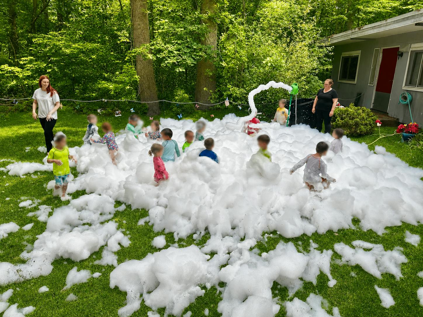 Group of children playing in a large pile of foam in a backyard