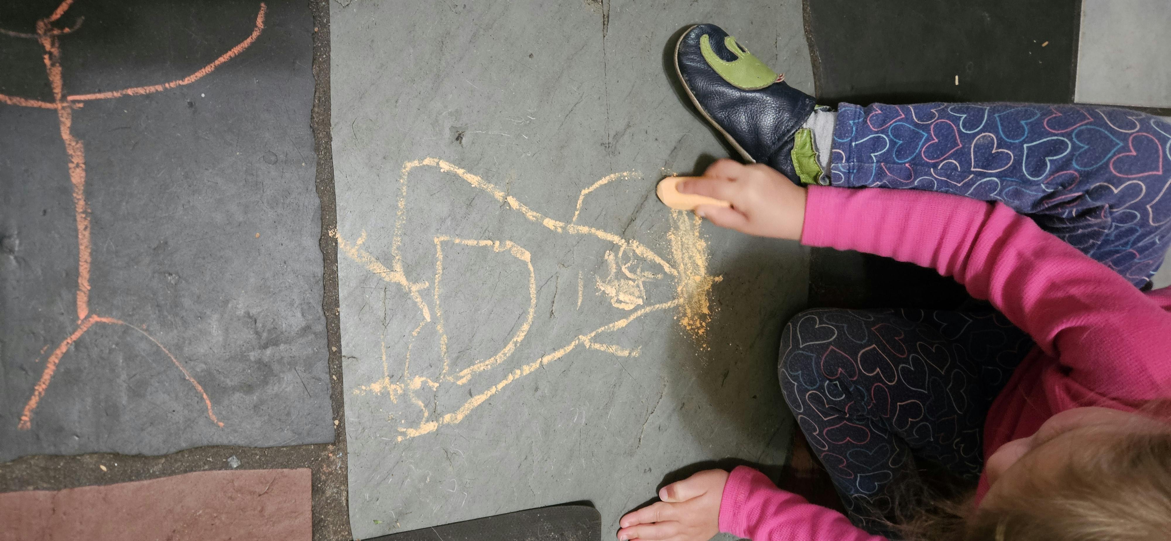Child drawing with chalk on a dark surface