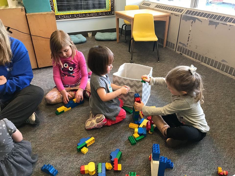 Children playing with building blocks on a classroom floor