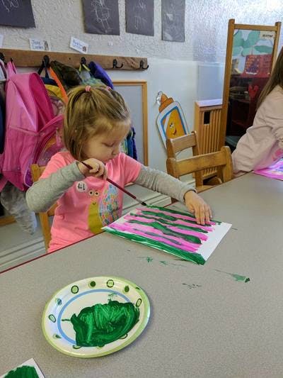 Child painting on paper at a table