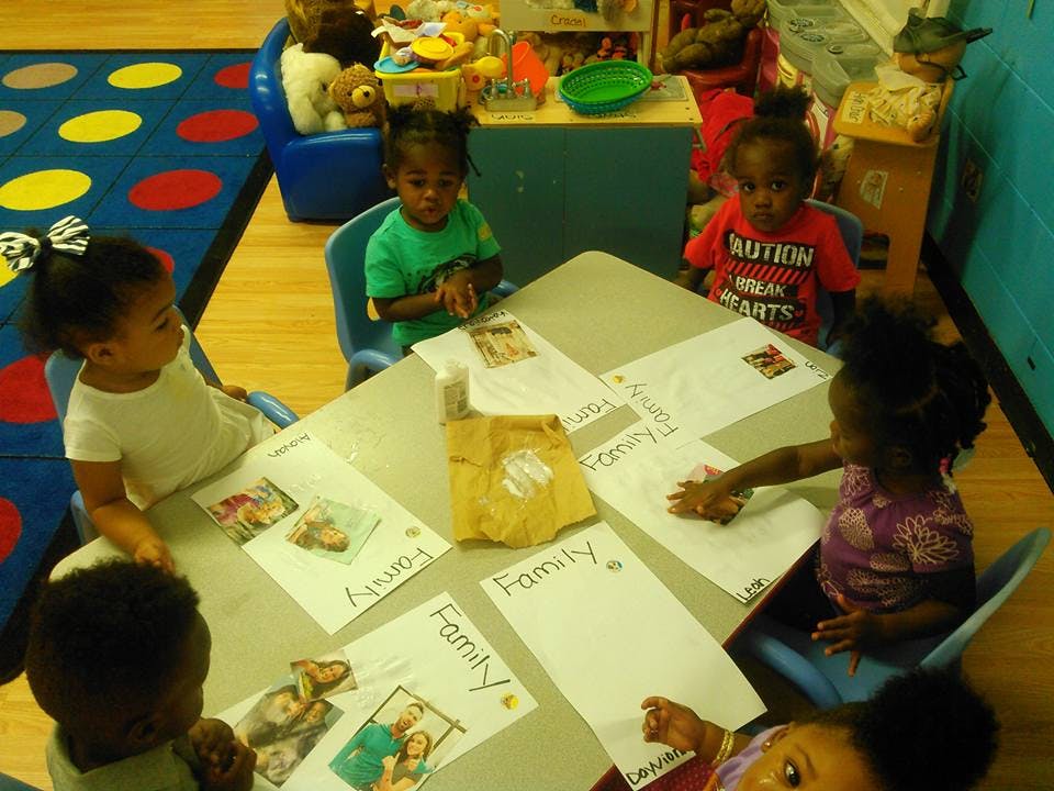 Children sitting at a table with papers that say "Family"