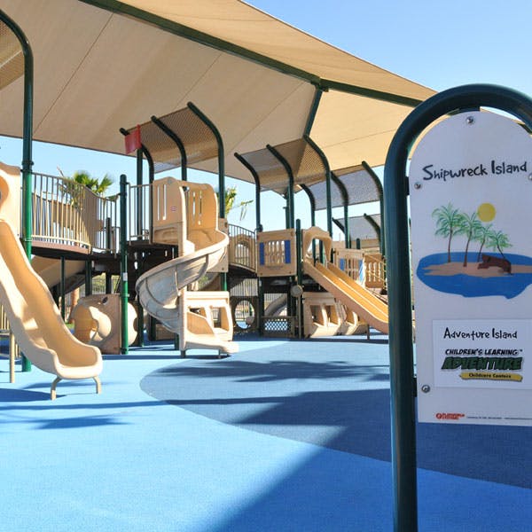 Playground with slides and climbing structures under a shade canopy